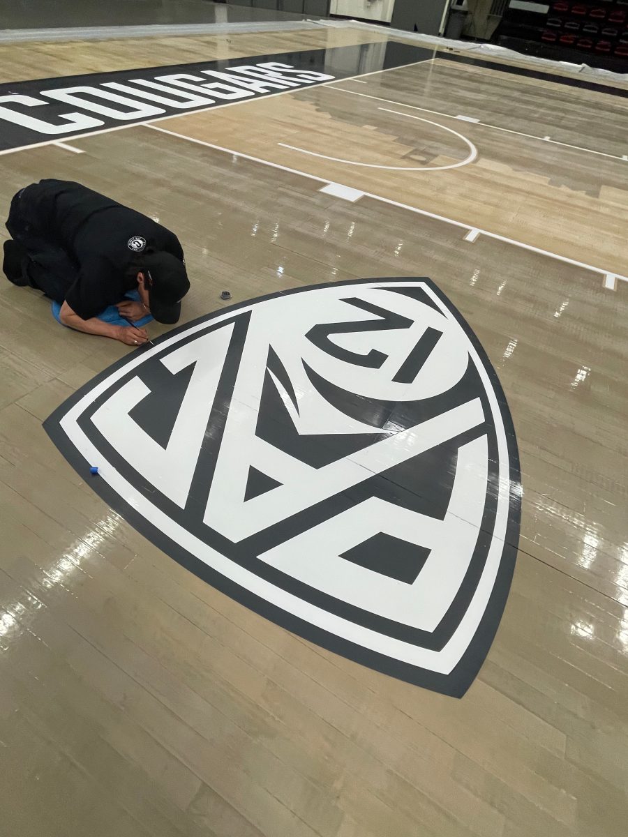 Touching up the PAC12 logo at WSU Cougars, Pullman, WA - on their portable basketball court by COURTSPORTS.